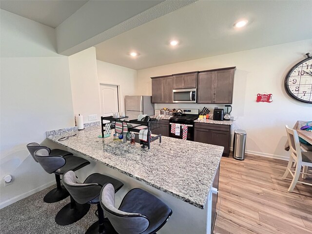 kitchen with dark brown cabinetry, a breakfast bar area, a peninsula, and appliances with stainless steel finishes