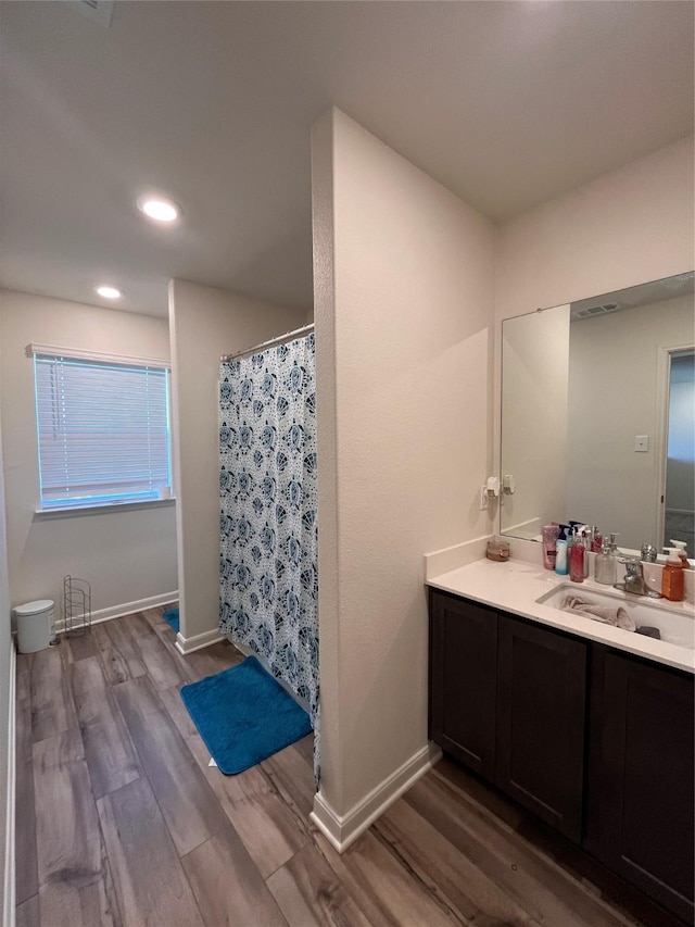 bathroom featuring baseboards, recessed lighting, vanity, and wood finished floors