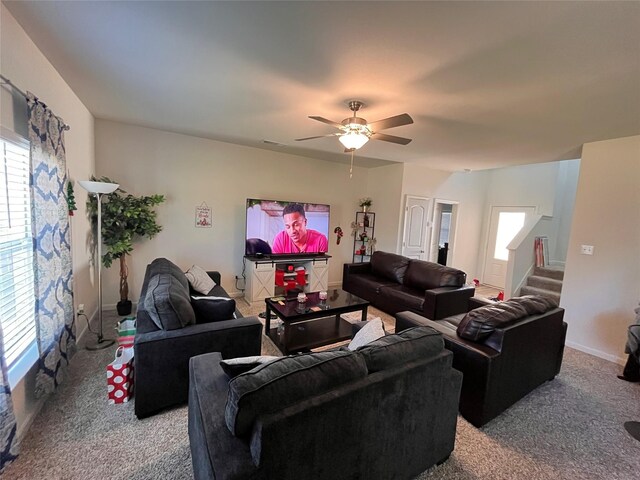 carpeted living area featuring visible vents, stairway, and a ceiling fan