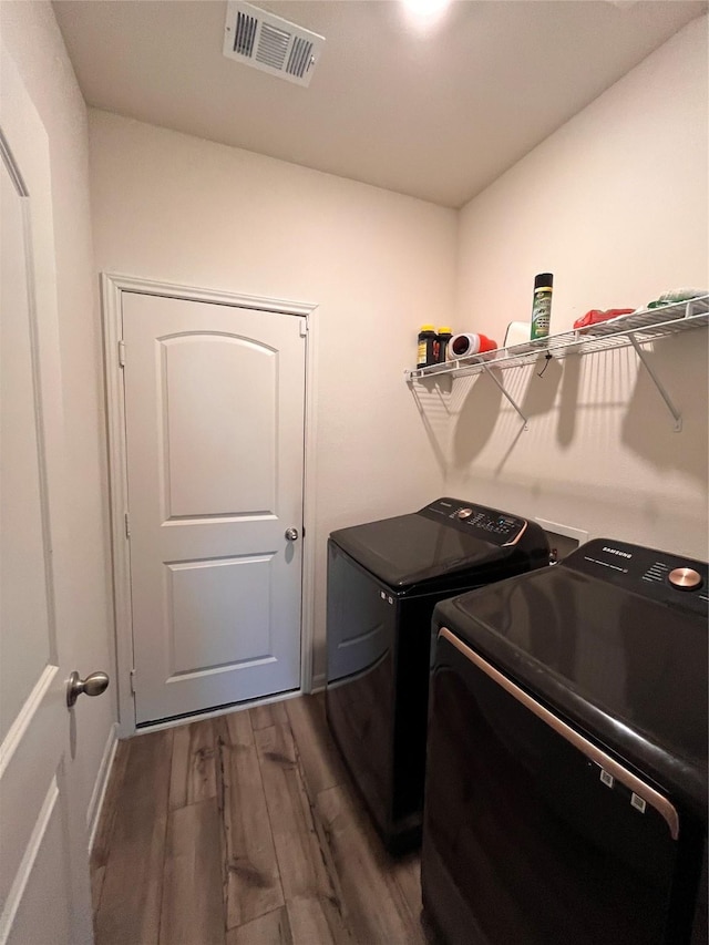 washroom featuring dark wood-style flooring, baseboards, visible vents, independent washer and dryer, and laundry area