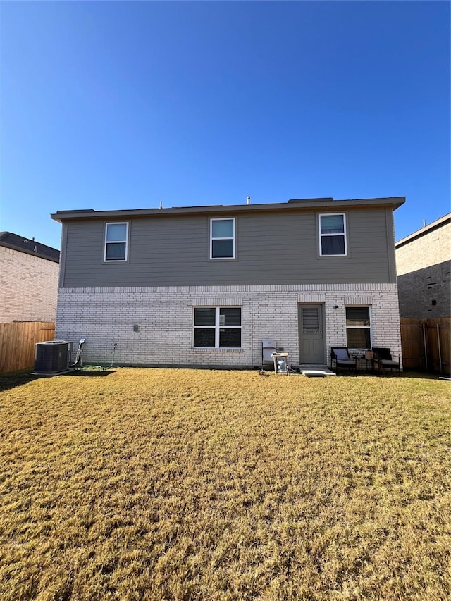 back of property with brick siding, central AC, fence, and a lawn