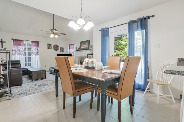 dining space featuring vaulted ceiling, light tile patterned floors, and ceiling fan with notable chandelier