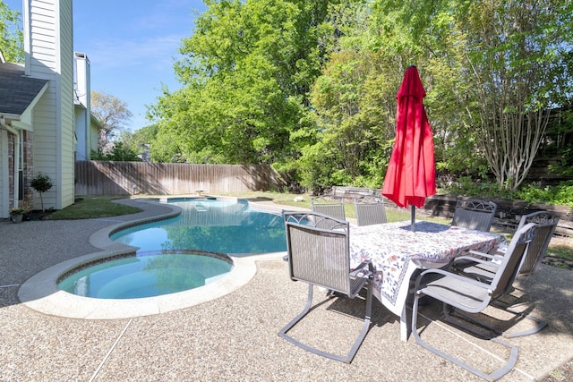 view of swimming pool with a pool with connected hot tub, a patio, a fenced backyard, and outdoor dining area