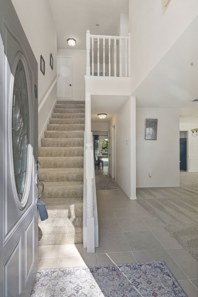 entrance foyer featuring tile patterned flooring, stairway, a towering ceiling, and baseboards