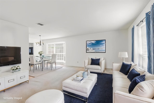 living area with light carpet, visible vents, and an inviting chandelier