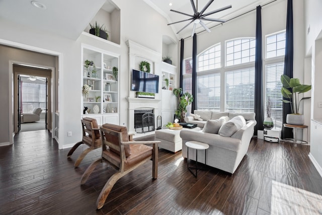 living room with plenty of natural light, baseboards, a towering ceiling, and built in shelves