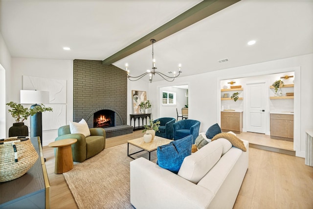 living room with lofted ceiling with beams, light wood-style flooring, visible vents, a brick fireplace, and a notable chandelier