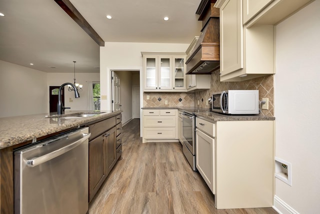 2312 Royce Dr, Arlington, TX 76016 - kitchen featuring custom range hood, tasteful backsplash, light wood-style floors, appliances with stainless steel finishes, and a sink