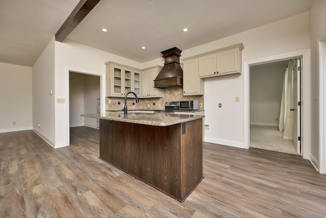 2312 Royce Dr, Arlington, TX 76016 - kitchen with a center island with sink, appliances with stainless steel finishes, wood finished floors, premium range hood, and backsplash