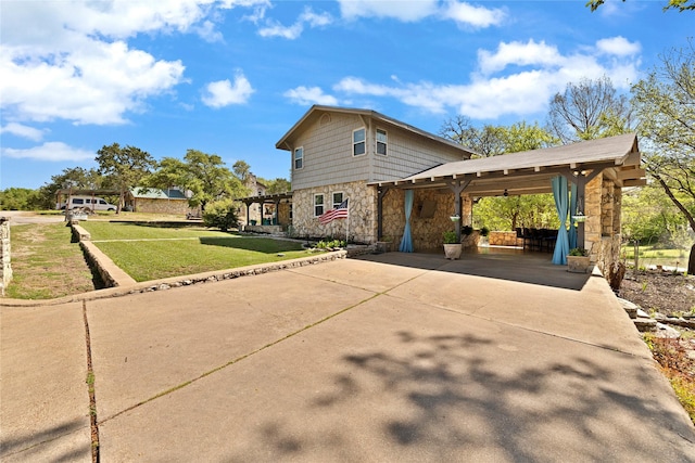 view of side of property with driveway, stone siding, and a lawn