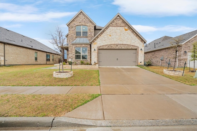 french country home featuring driveway, stone siding, an attached garage, a front yard, and brick siding