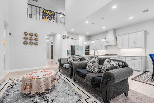 living area featuring arched walkways, visible vents, recessed lighting, light tile patterned flooring, and baseboards