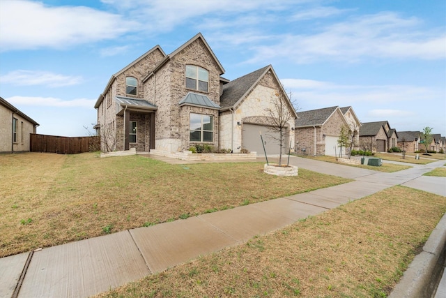 french provincial home with a standing seam roof, metal roof, a front yard, fence, and concrete driveway