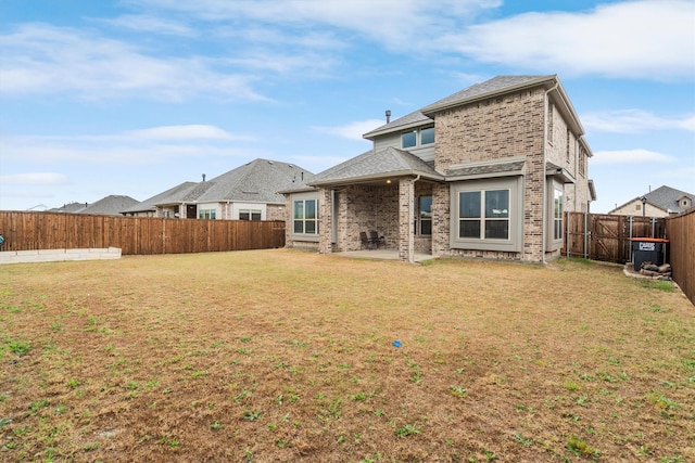 rear view of property featuring roof with shingles, a patio area, brick siding, a fenced backyard, and a lawn
