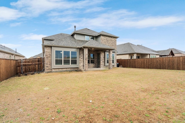 back of property featuring a shingled roof, a lawn, a fenced backyard, a patio, and brick siding