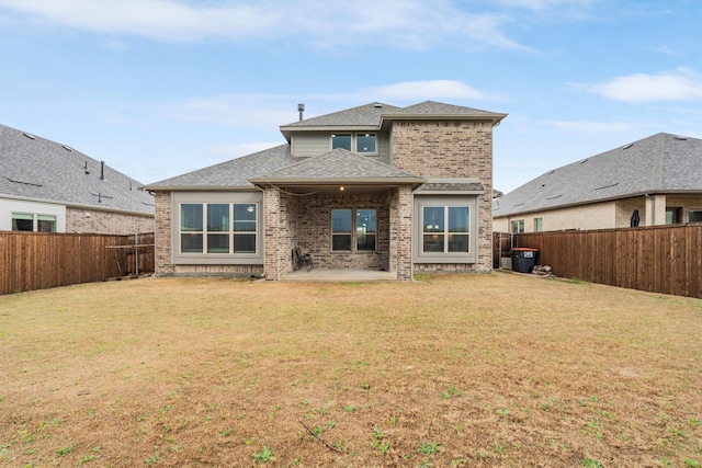 back of property with a patio, brick siding, a fenced backyard, and a lawn