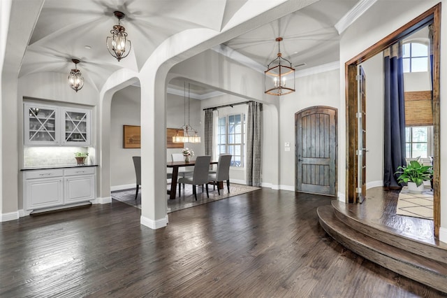 entrance foyer featuring arched walkways, a notable chandelier, and baseboards