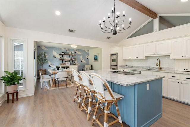 kitchen with white cabinetry, visible vents, a kitchen island, a sink, and stainless steel double oven