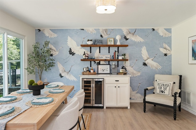 bar with wallpapered walls, visible vents, a dry bar, light wood finished floors, and beverage cooler