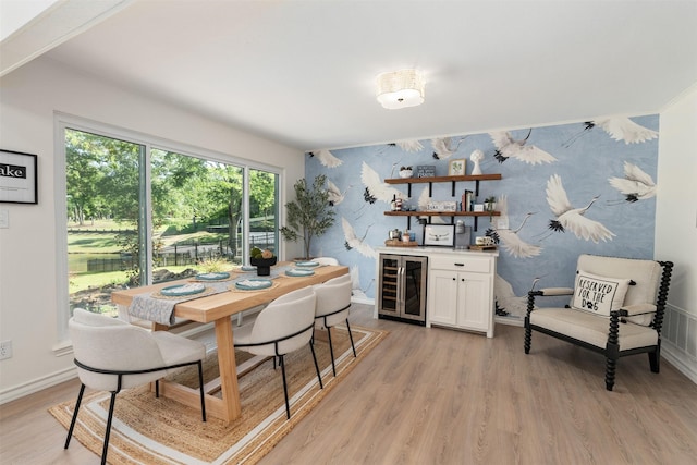 dining room featuring a dry bar, wine cooler, wallpapered walls, light wood finished floors, and baseboards