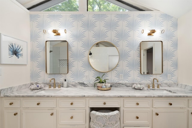full bath featuring a sink, double vanity, vaulted ceiling, and wallpapered walls