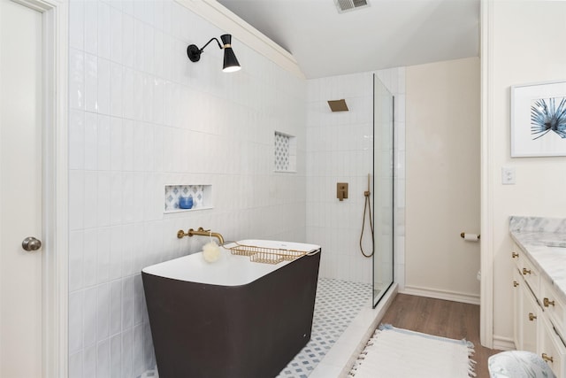 bathroom featuring vanity, walk in shower, visible vents, tile walls, and wood finished floors