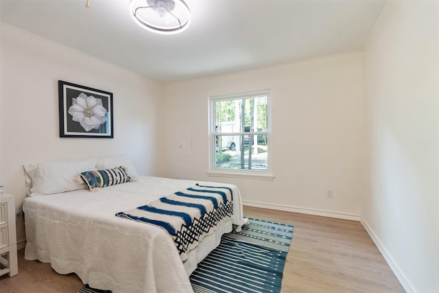 bedroom featuring crown molding, baseboards, and wood finished floors