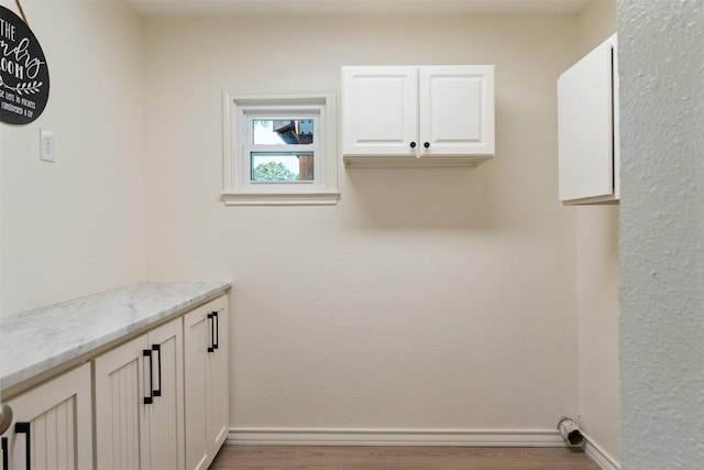 laundry room with baseboards and wood finished floors