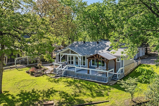 back of property with a yard, fence, a deck, and a shingled roof
