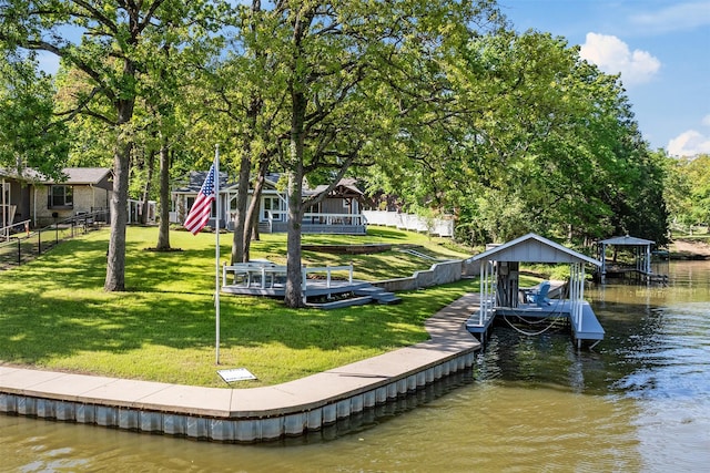 view of dock with a water view, a yard, fence, and boat lift