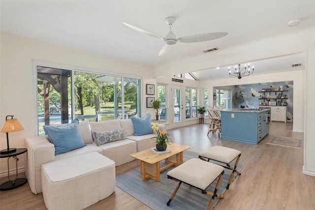 living room with light wood-style flooring, visible vents, a wealth of natural light, and ceiling fan with notable chandelier