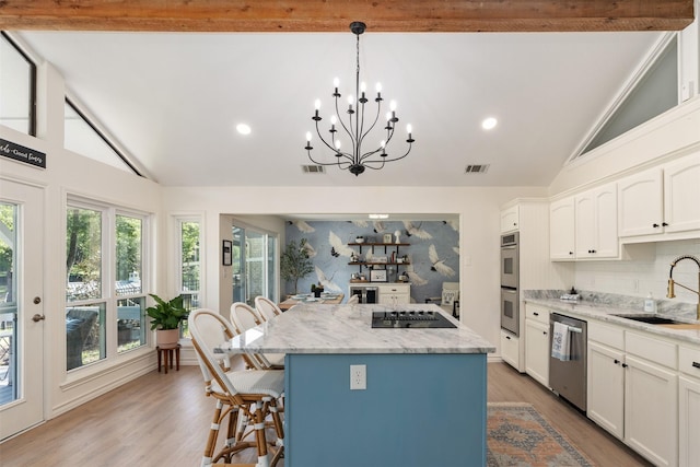kitchen featuring a kitchen breakfast bar, a kitchen island, visible vents, appliances with stainless steel finishes, and a sink