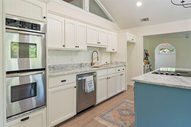 kitchen featuring vaulted ceiling, visible vents, appliances with stainless steel finishes, a sink, and backsplash