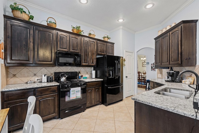 5929 Black Bass Dr, Fort Worth, TX 76179 - kitchen with arched walkways, a sink, dark brown cabinets, black appliances, and decorative backsplash