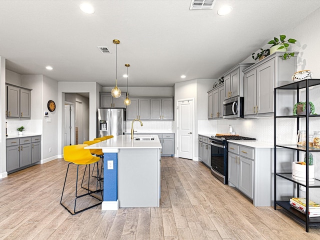 14624 Bootes Dr, Haslet, TX 76052 - kitchen with stainless steel appliances, a sink, gray cabinetry, light wood-type flooring, and decorative backsplash