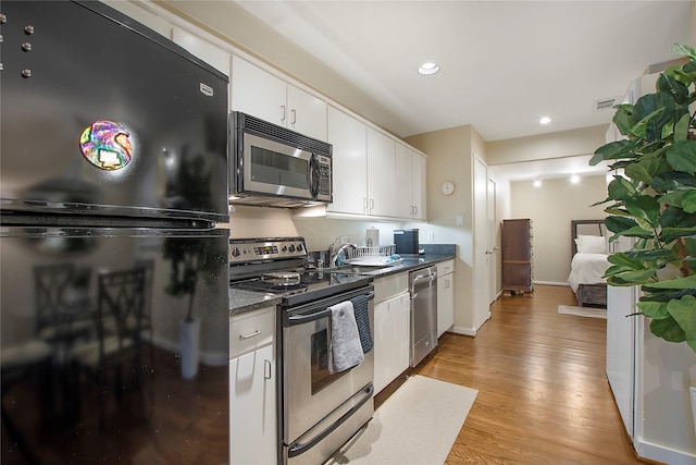 4241 Buena Vista St Unit 14, Dallas, TX 75205 - kitchen with light wood-type flooring, recessed lighting, white cabinetry, dark countertops, and appliances with stainless steel finishes