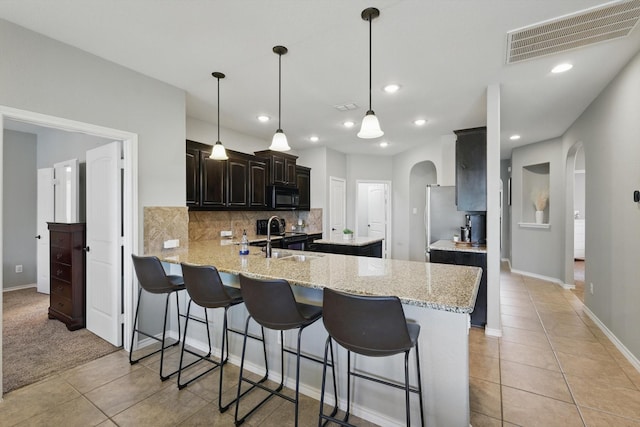 336 Avila Ln, Fort Worth, TX 76052 - kitchen with arched walkways, black microwave, light tile patterned floors, a peninsula, and recessed lighting