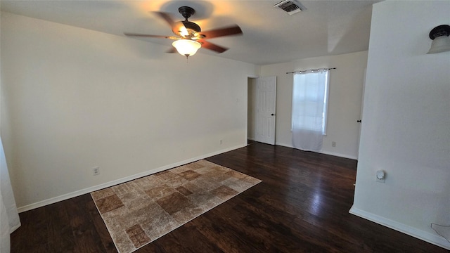 spare room with dark wood-type flooring, visible vents, baseboards, and a ceiling fan