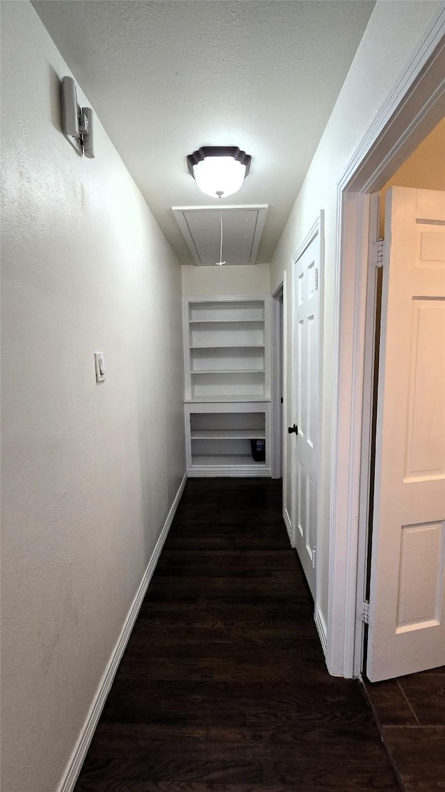 hall with built in shelves, baseboards, attic access, and wood finished floors