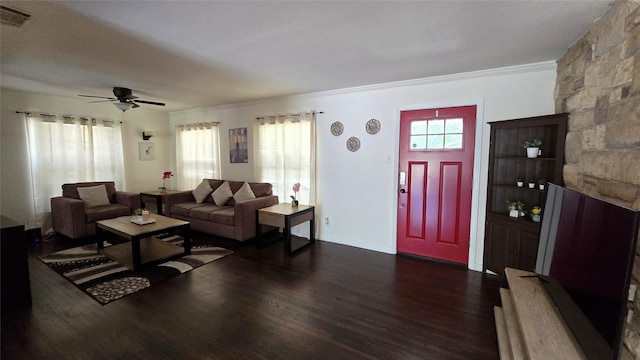 living area with visible vents, baseboards, dark wood-style flooring, ceiling fan, and crown molding
