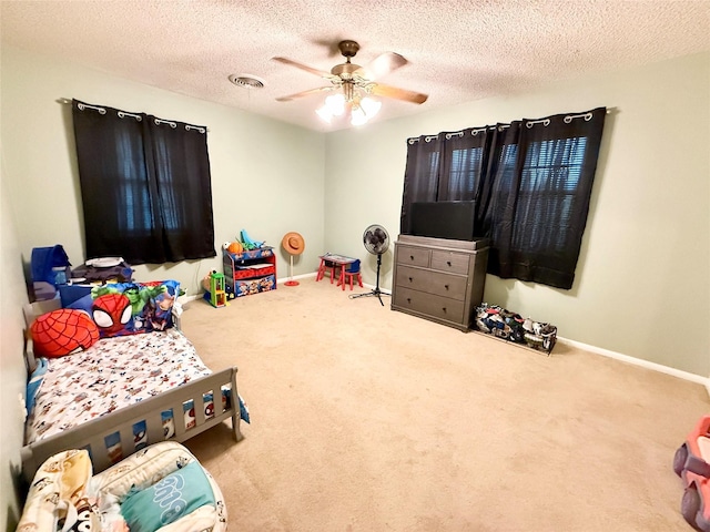 game room featuring baseboards, ceiling fan, a textured ceiling, and carpet