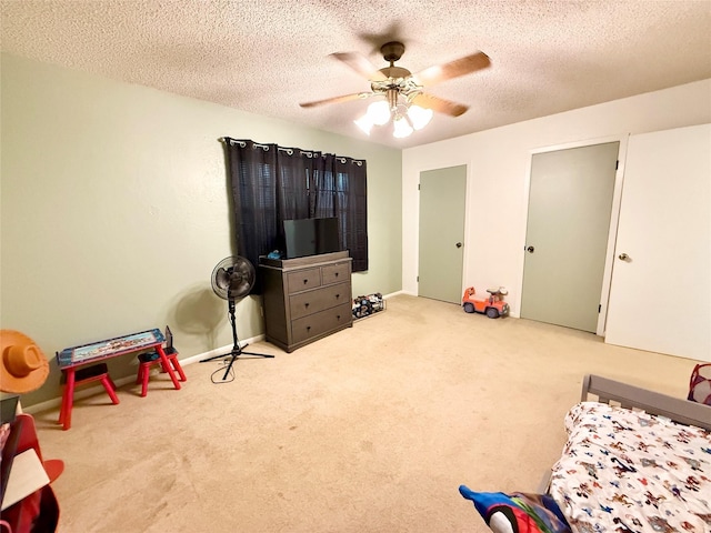 recreation room with a textured ceiling, a ceiling fan, and carpet floors