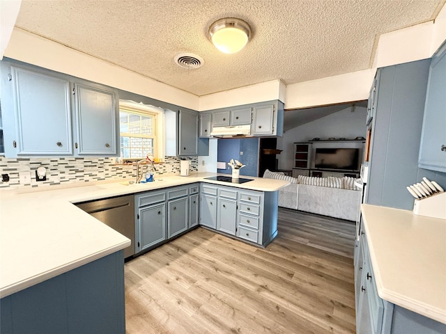 kitchen featuring a peninsula, under cabinet range hood, black electric cooktop, a sink, and a textured ceiling