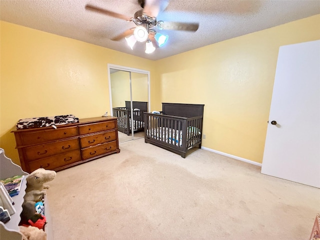 carpeted bedroom with a textured ceiling, ceiling fan, and a closet