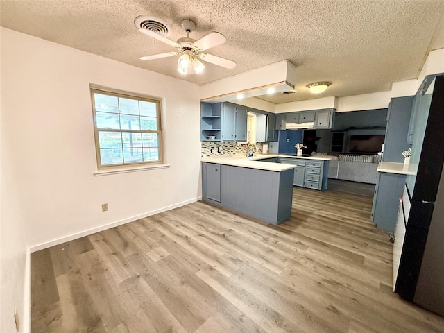 kitchen featuring wood finished floors, open shelves, a textured ceiling, light countertops, and a peninsula