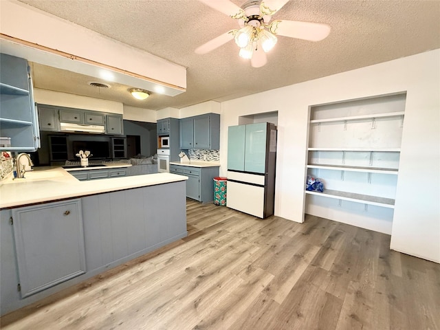 kitchen featuring a sink, open shelves, light wood-style flooring, a peninsula, and white appliances