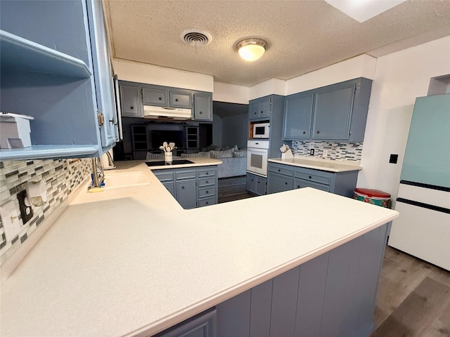 kitchen with tasteful backsplash, white appliances, visible vents, a textured ceiling, and dark wood-type flooring