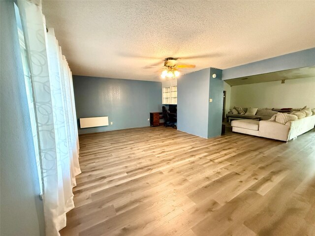 unfurnished living room featuring a textured ceiling, wood finished floors, and ceiling fan