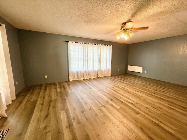 unfurnished room with a ceiling fan, wood finished floors, and a textured ceiling