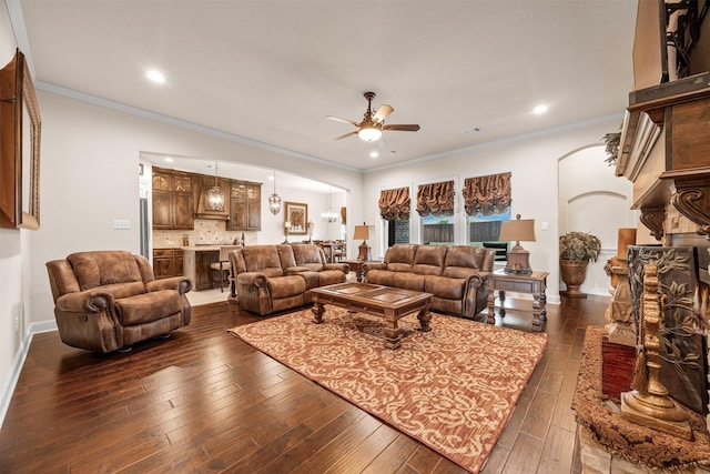 living area with arched walkways, ceiling fan, dark wood-style floors, crown molding, and recessed lighting